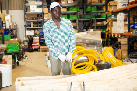 Warehouse worker pushing cart with planks