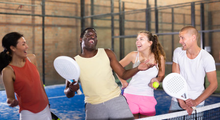 Two happy couples after playing padel on tennis courtの写真素材