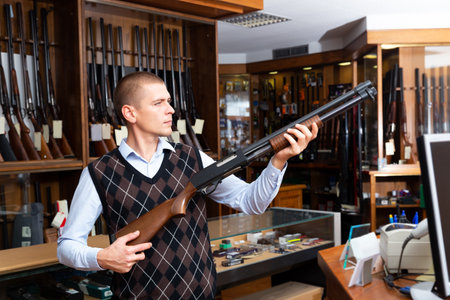 Portrait of an arms shop salesman with pump-action shotgun in handsの写真素材