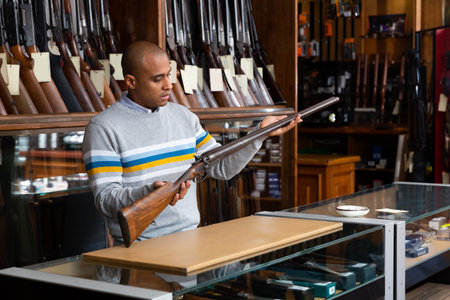 Portrait of male standing with rare collectible rifle in hunting shopの写真素材