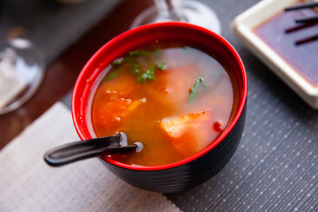 Spicy asian tomato soup in red bowlの写真素材