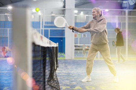 Padel game - woman with partners plays on tennis court