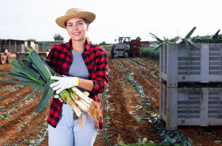 Woman posing with leek crop on fieldの写真素材