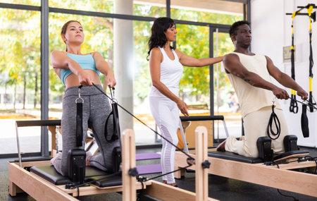 Multiracial people having pilates workout on reformers with trainerの写真素材