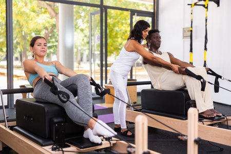 Girl doing pilates exercises with reformer bed in studio. Active lifestyle and fitness conceptの写真素材