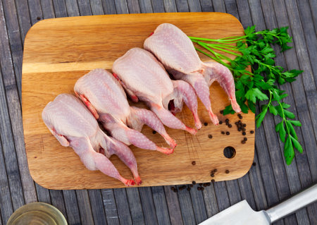 Raw quails with greens and spices prepared for cooking on wooden tableの写真素材