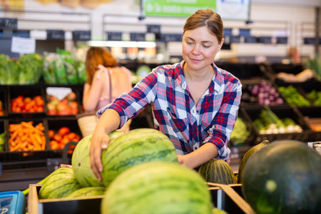 Young woman choosing ripe watermelon while shopping in supermarketの写真素材