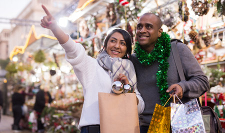 Married couple looking for decorations on Christmas street market while shoppingの写真素材