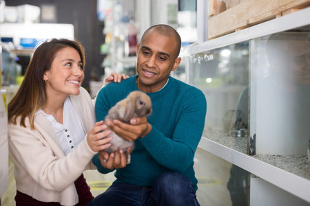 Family couple holding rabbit together in pet shop