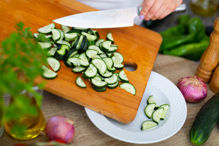 Slicing fresh cucumber on cutting boardの写真素材
