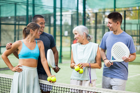 Two pairs of padel players are happily discussing past game on an open courtの写真素材