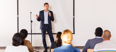 Confident man with microphone speaking at corporate business event