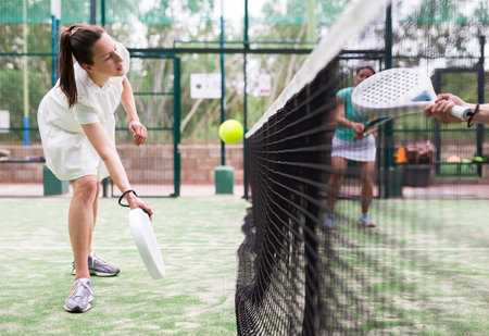 Padel game - woman with partners plays on tennis courtの写真素材