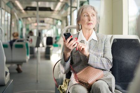 Woman with smartphone sitting in tramの写真素材
