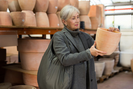 Aged woman choosing pots for house plants in gardening marketの写真素材
