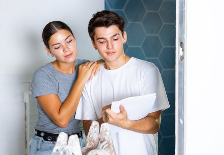 Interested couple making notes while planning overhaul of apartment