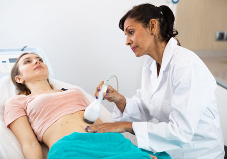 Cosmetologist making ultrasound lifting procedure in abdominal zonesの写真素材