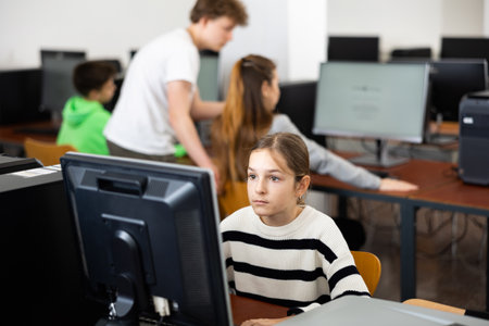 Pupils using computers at lesson, teacher teaching them in class roomの写真素材