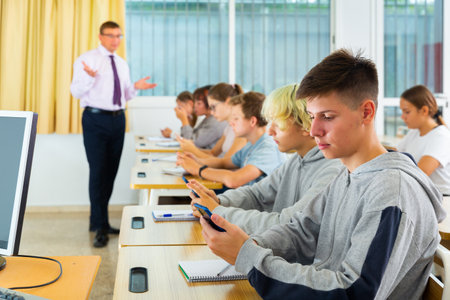 Teenage students using smartphones during lessonの写真素材