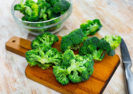 Cutting and cooking green broccoli on wooden textured backdropの写真素材