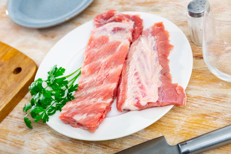Raw pork ribs with parsley on wooden table. Cooking foodの写真素材