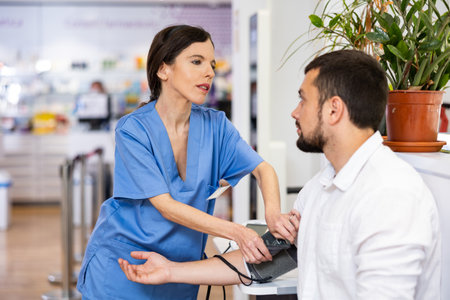 Female pharmacist checking blood pressure of customerの写真素材