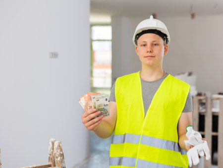 Satisfied young man with bunch of cash for part-time jobの写真素材