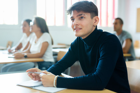 Positive young man attending lecture in collegeの写真素材