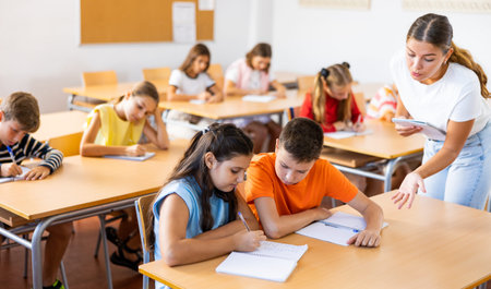 Tween boy peeking at workbook of girl classmate at lesson