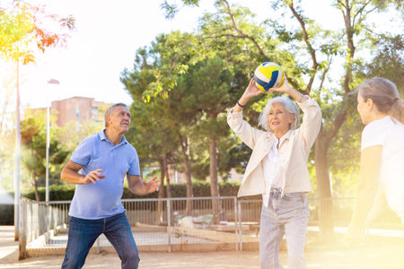 Positive multiracial friends of different ages throwing up a volleyball ball in a circle in the parkの写真素材