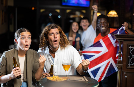 Enthusiastic couple cheering for favorite team of United Kingdom in sports barの写真素材