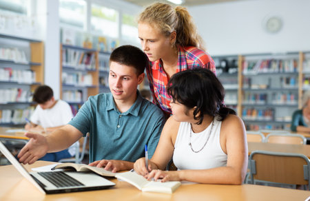Schoolchildren help each other solve the task in school libraryの写真素材