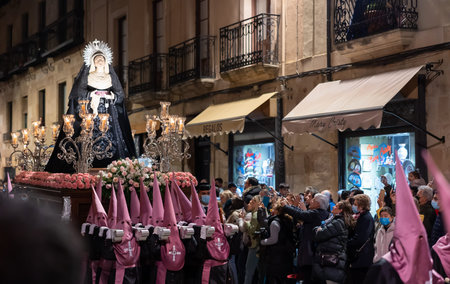 Procession of flagellants carrying Paso with Mother Mary statue in Salamanca