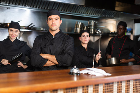 Portrait of team of cooks led by male chef in restaurant kitchenの写真素材