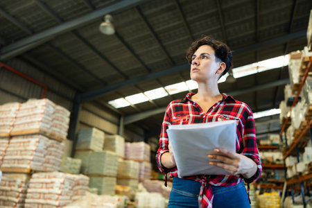 Female storekeeper checks availability of goods with documents in the building materials warehouseの写真素材