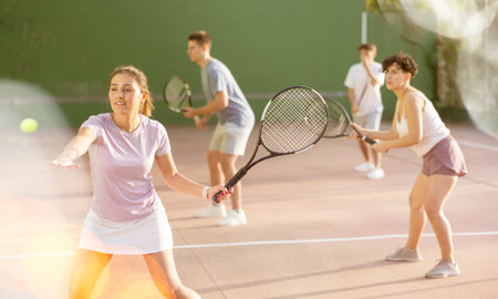 Expressive resolved fit girl playing frontenis ball friendly match on courtの写真素材