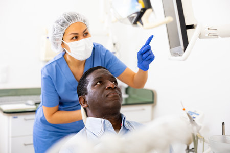 Man patient and woman dentist looking at monitor during consultationの写真素材