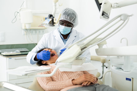 Orthodontist using tools and curing toothache of asian womanの写真素材
