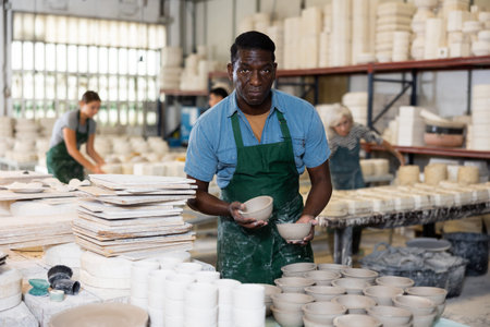 Portrait of african american man displaying cups at workshop