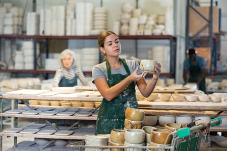 Young woman checks quality of pottery after being removed from plaster moldの写真素材