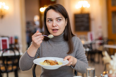 Woman tasting Viennese apple strudel during breakfast in cafeの写真素材