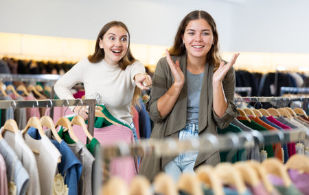 Cheerful young women pointing on clothes far away, spending time in a shopping mallの写真素材
