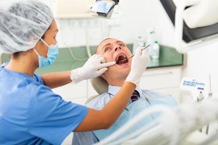 Female dentist examines the oral cavity of female patient. Dental treatment in dental clinicの写真素材