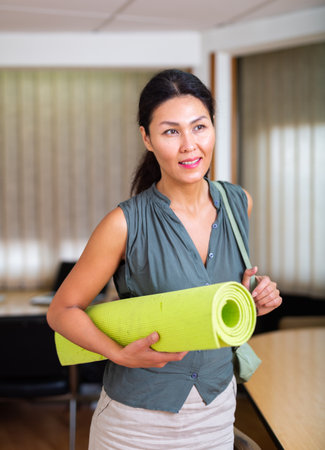 Asian businesswoman holding yoga mat in officeの写真素材