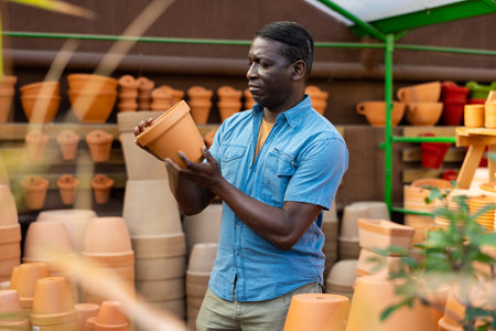 African american man choosing pots for flowers and trees in gardening marketの写真素材