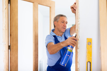 Male professional door installer fills gaps with mounting foam