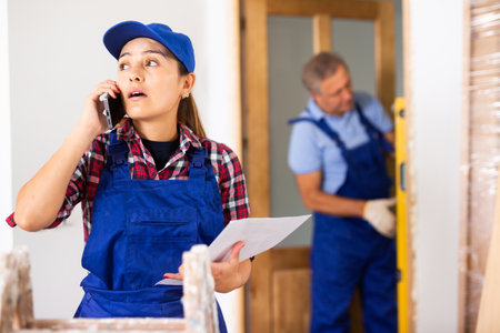 Woman construction manager talking on phone in apartmentの写真素材