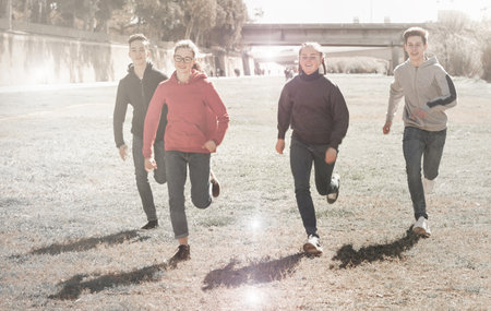 Cheerful teens running on green lawnの写真素材