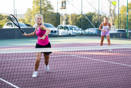 Sportive woman dressed in t-shirt and skirt playing tennis with partnerの写真素材