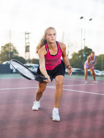 Sporty teenage girl tennis player playing tennis at court. View through tennis netの写真素材